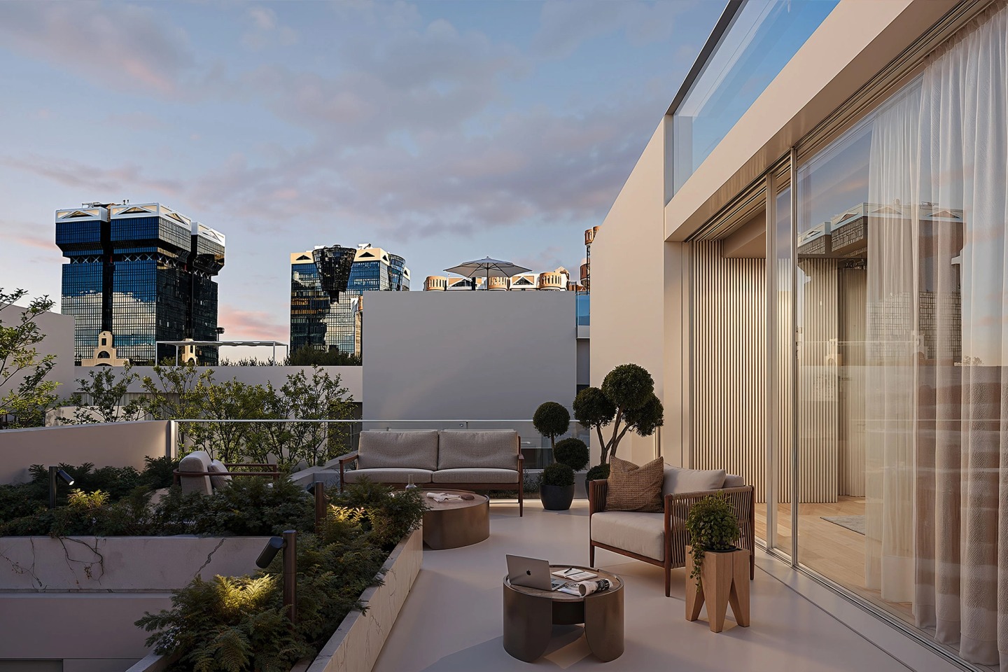 Terrace with sofas and plants at dusk, with the Amoreiras towers and a pink sky beyond.