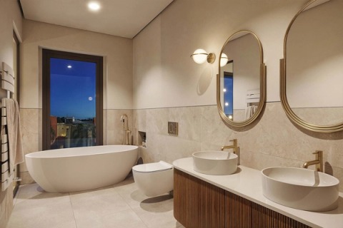 Bathroom with a freestanding bath, a double fluted-timber vanity and oval brass mirrors.