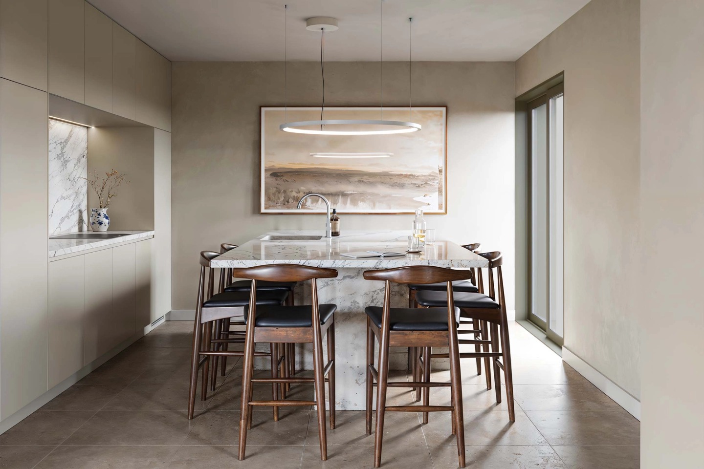 Kitchen with a marble island, tall timber stools and a circular pendant light.