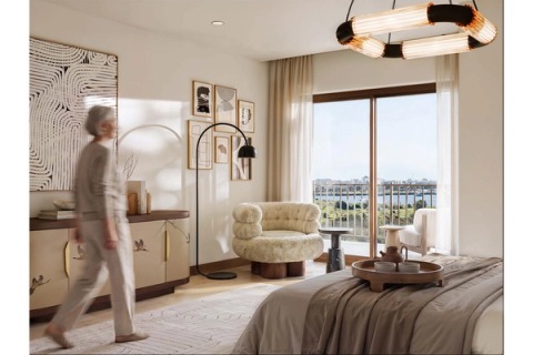Bright bedroom with an armchair by the window and a balcony overlooking the river.