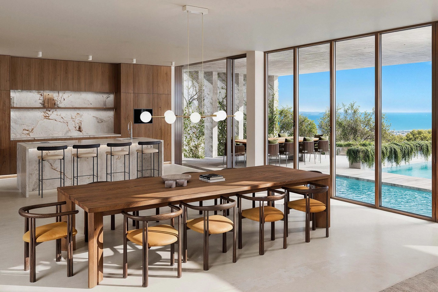Kitchen with a marble island and a timber dining table, opening onto the pool and the sea.