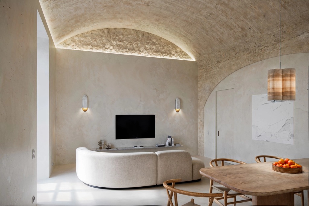 Living room under a brick vault, with a curved sofa and dining table, at Villa Pinto in Olhão.