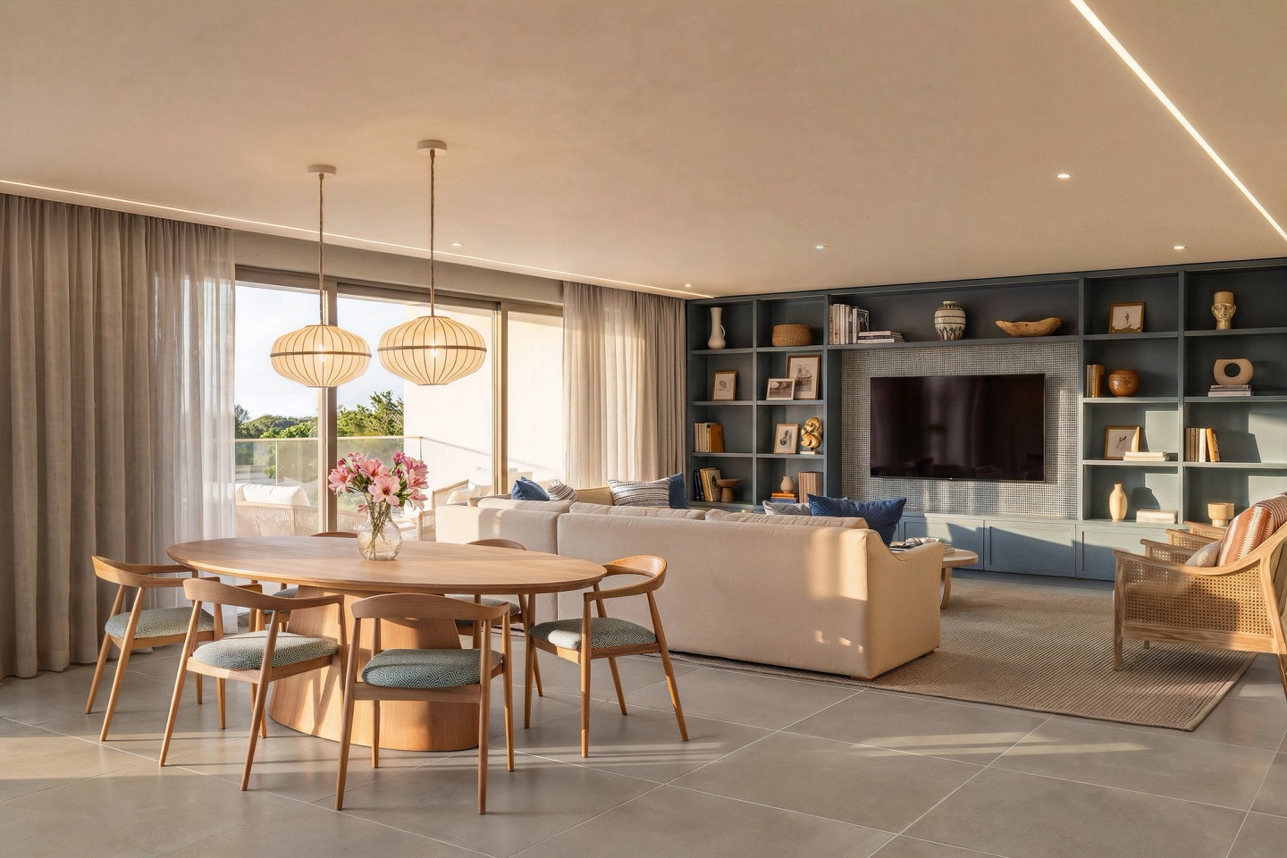 Timber dining table with pendant lights and a living room with shelving beyond, in a Conrad Algarve apartment.