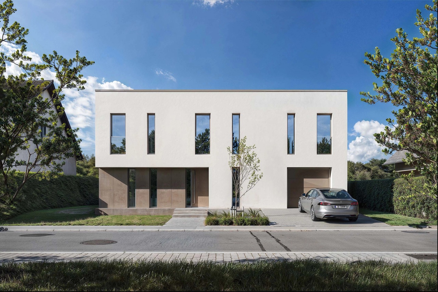 Front of the house in Junglinster, with a garden and the neighbourhood trees.