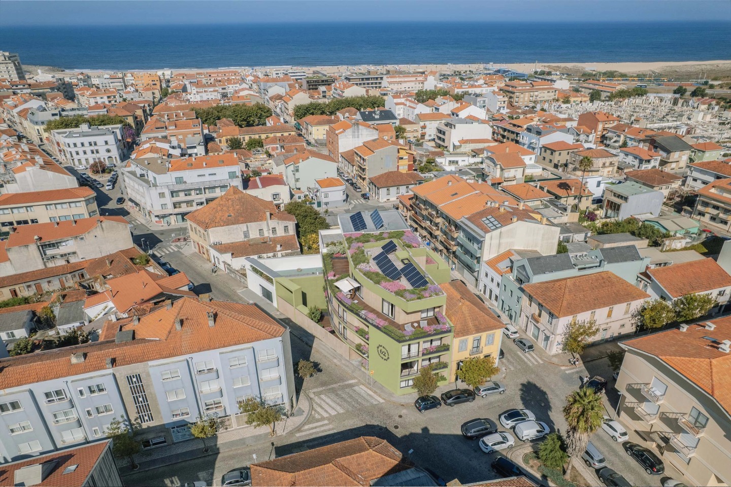 Aerial view of Espinho with 62 The Flat Gardens among red roofs and the sea beyond.