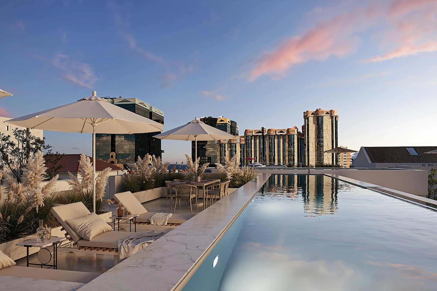 Rooftop pool at sunset, with sun loungers, parasols and the city of Lisbon beyond.