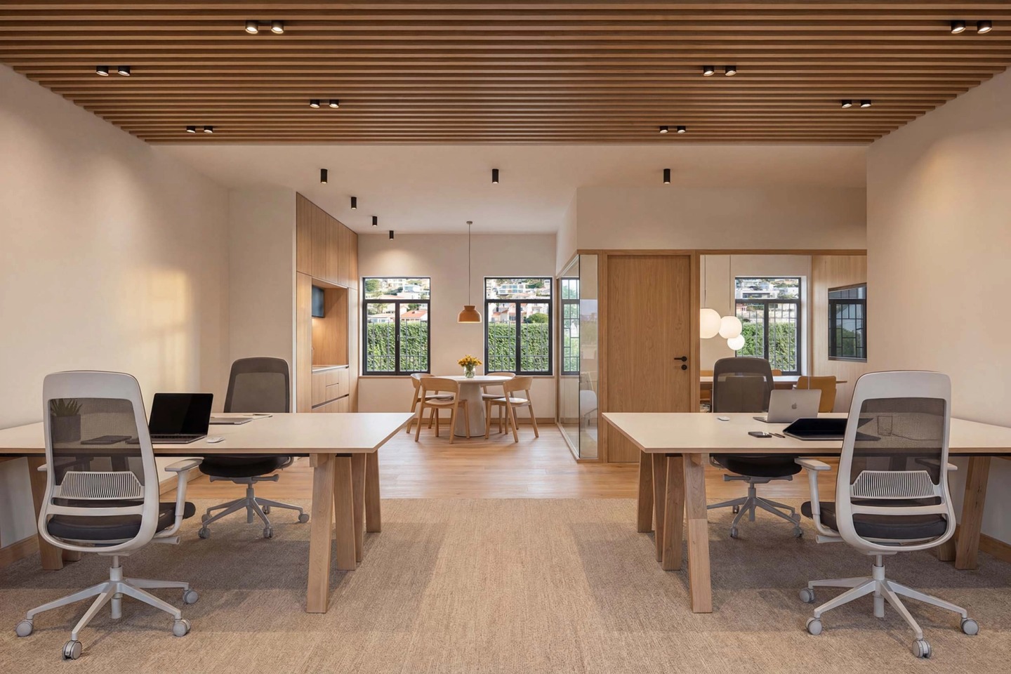 Coworking space with desks, ergonomic chairs and a timber slat ceiling.