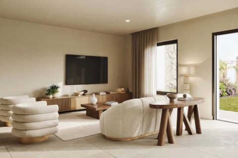 Light living room with curved armchairs, a sofa and TV, opening onto the garden.