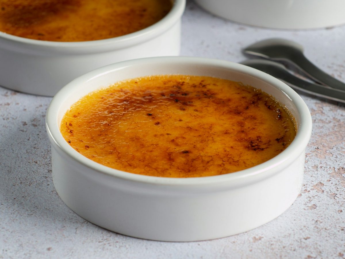 Crème brûlée in a white ramekin with a caramelized, golden-brown sugar top.