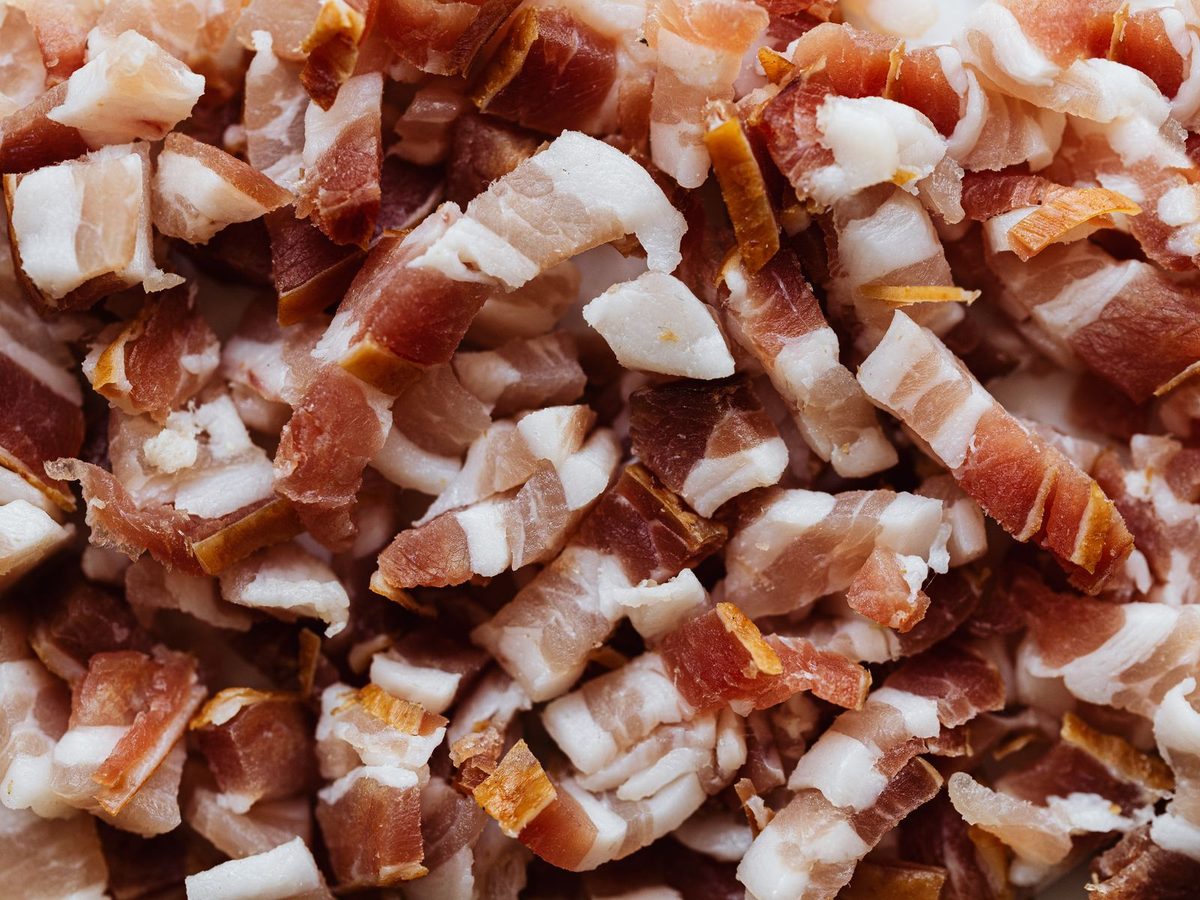 A pile of raw smoked pork belly cut into small batons.