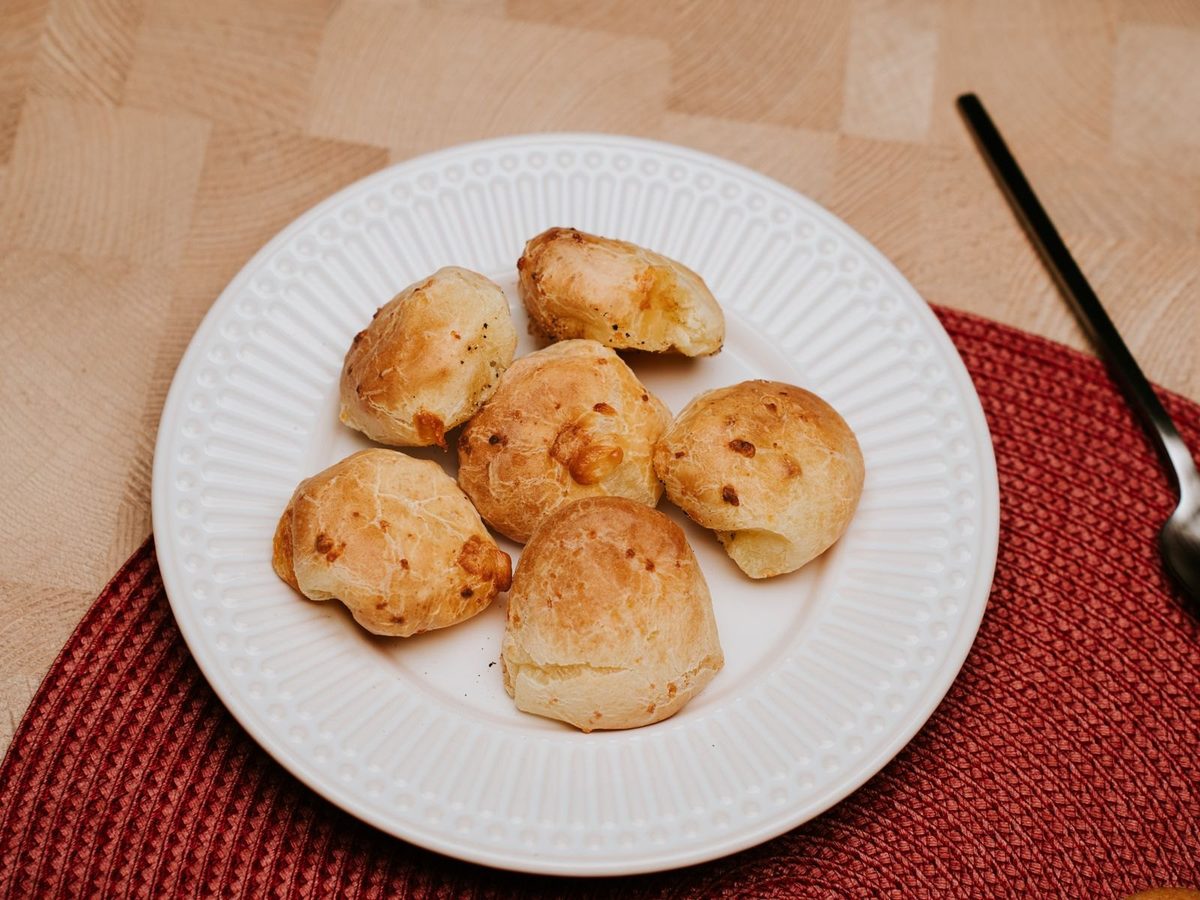 A plate of golden cheese puffs on a red woven placemat.