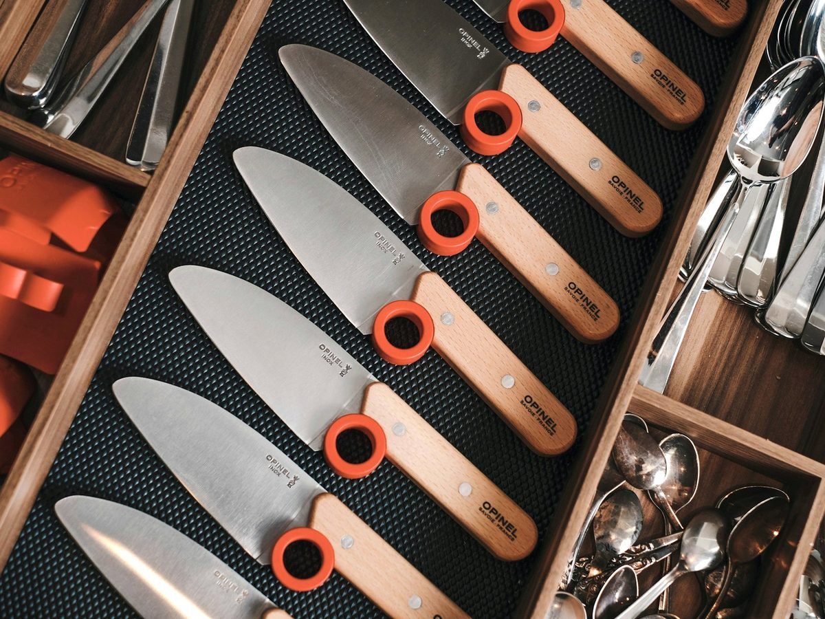 Opinel kitchen knives with beech handles lined up in a drawer.