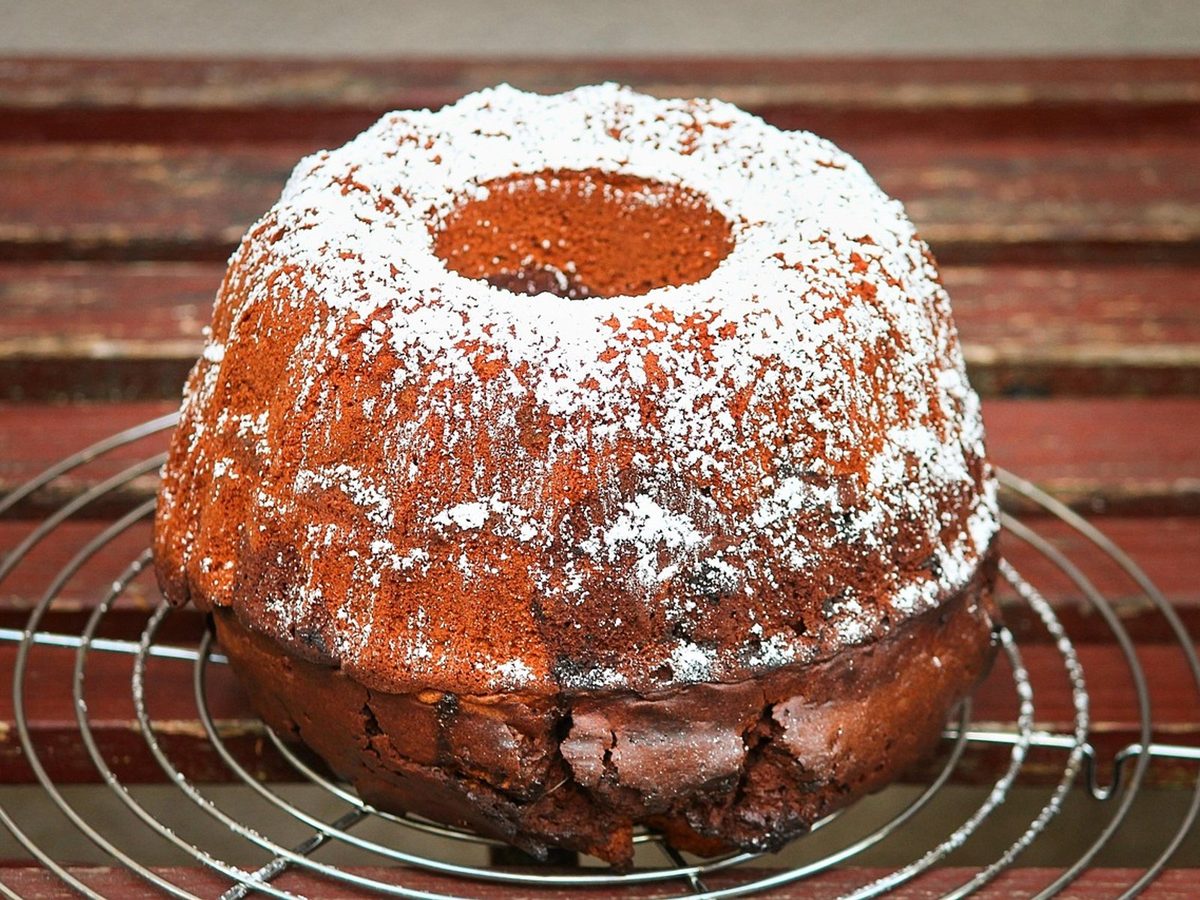 A fluted ring cake dusted with icing sugar, cooling on a wire rack.