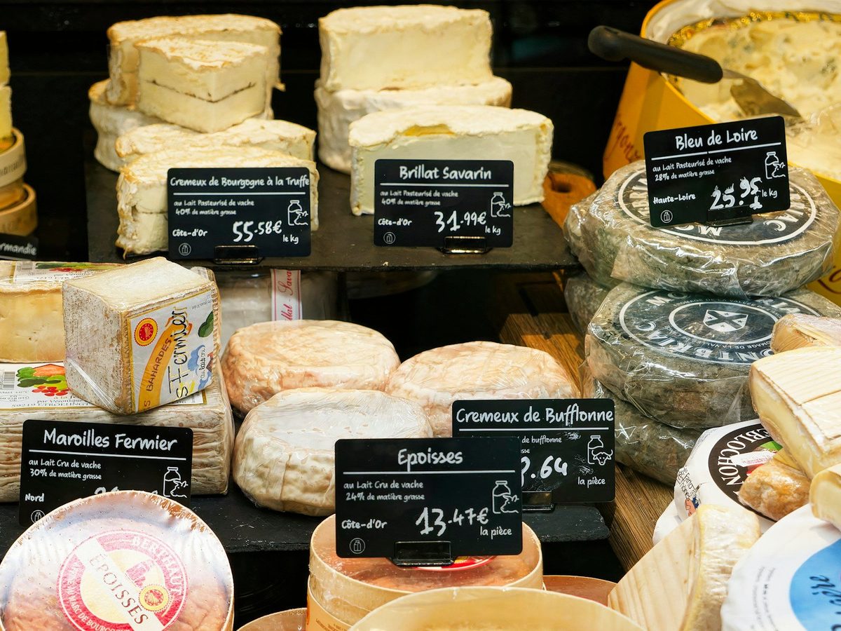 A French cheese counter with soft cheeses and handwritten price labels.
