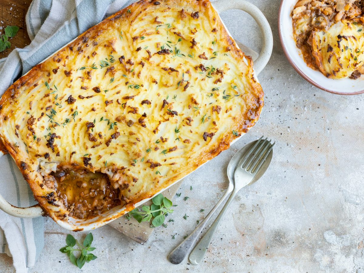 A baking dish of hachis parmentier with a golden mashed potato top and a serving scooped out.