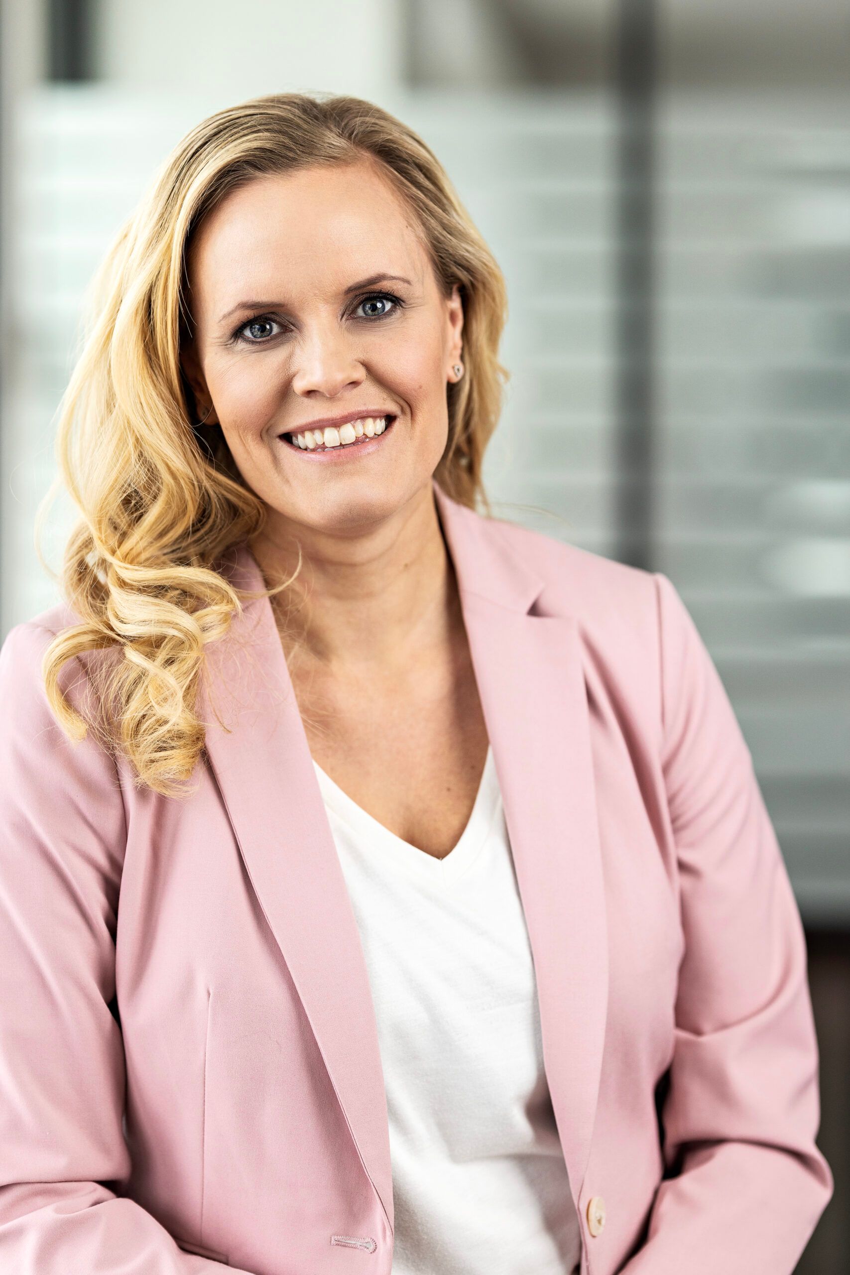Preview of: Smilende blond kvinde i lyserød blazer og hvid bluse