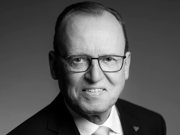 Sort-hvidt portræt af en ældre mand med briller, jakkesæt og slips.