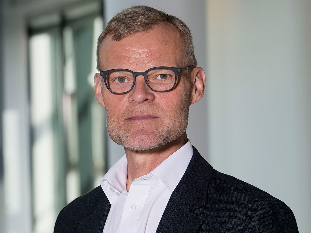 Preview of: Mand med kort hår, skægstubbe og briller iført hvid skjorte og mørk jakke