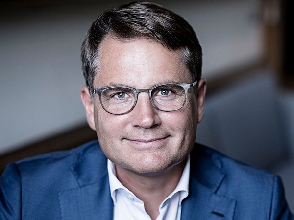 Portræt af en mand med briller, kort mørkt hår, blå jakke og hvid skjorte
