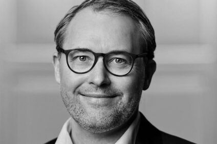 Preview of: Sort-hvidt portræt af en smilende mand med briller og kort hår