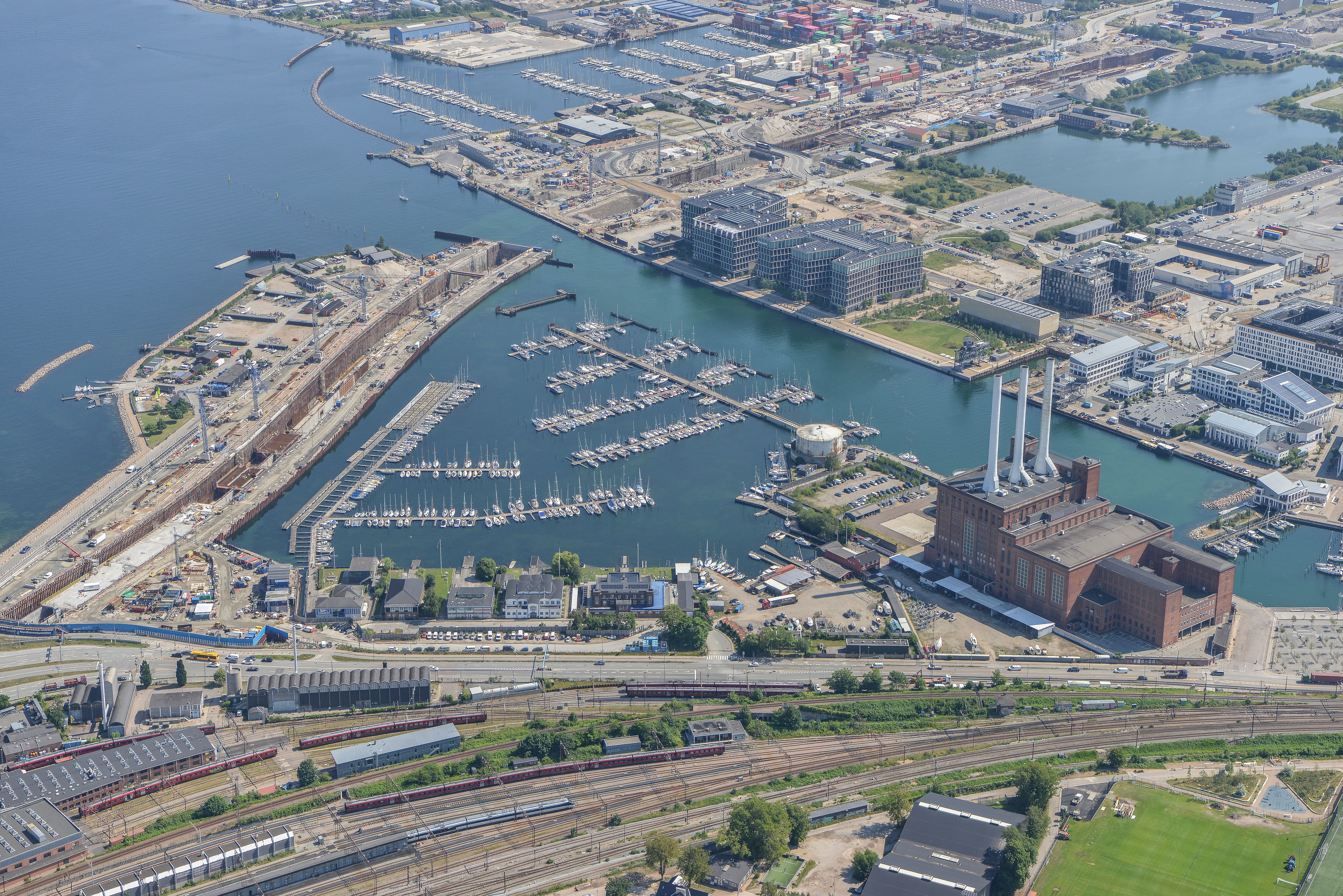 Preview of: Høj murstensindustribygning med hvid skorsten ved havnefronten