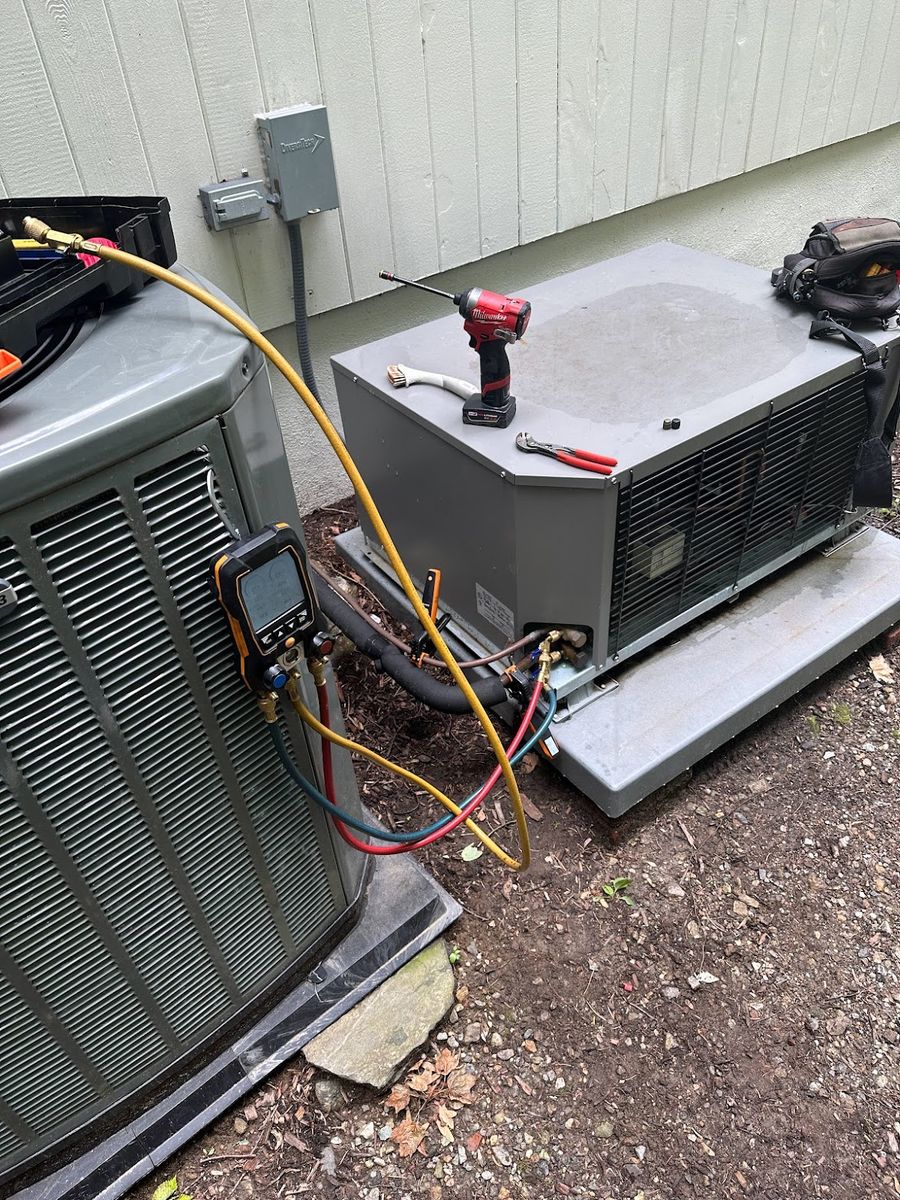 Art HVAC technician checking refrigerant pressures on an outdoor heat pump with digital manifold gauges