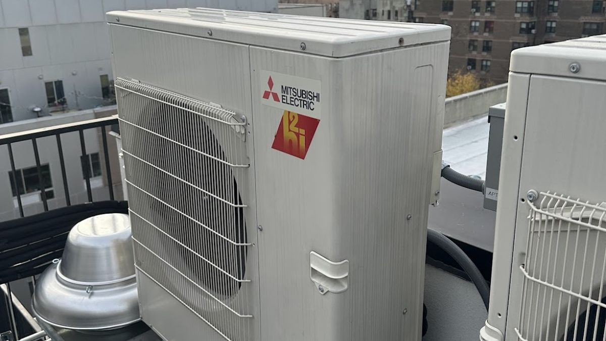 Art HVAC Technician Comparing a Heat Pump and a Traditional Gas Furnace During a NYC Residential Consultation Visit