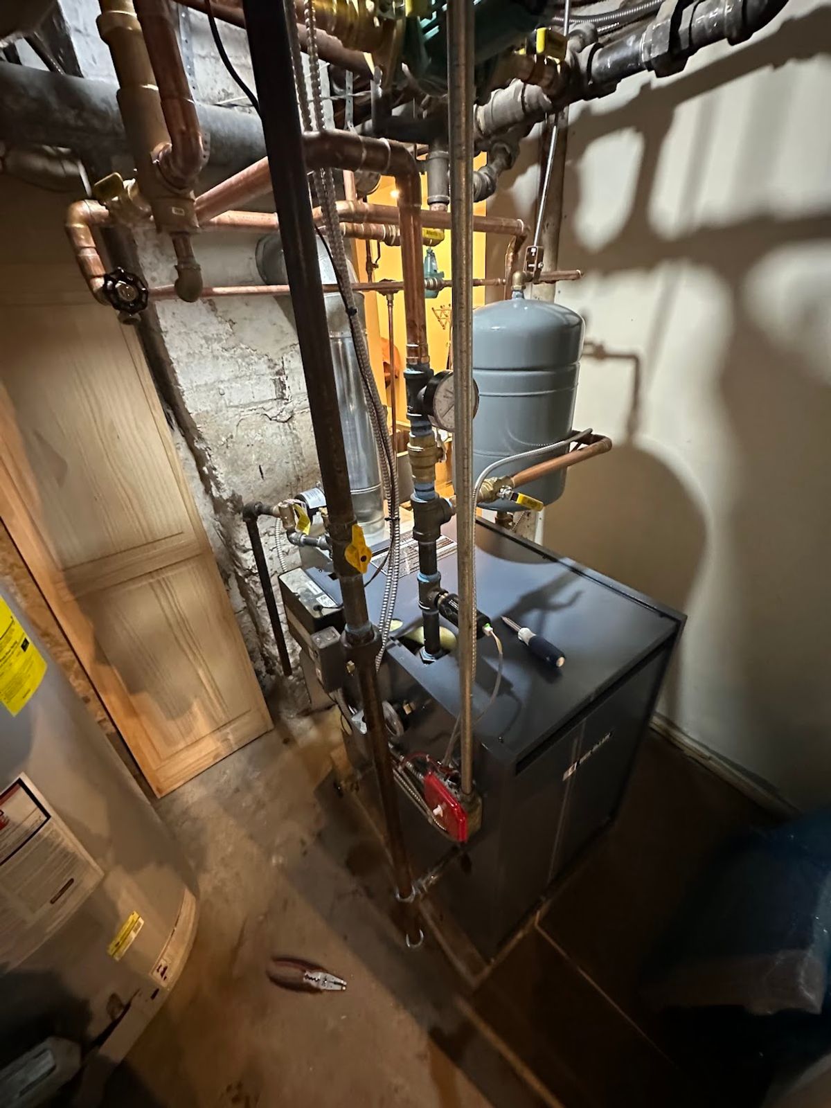 Gas-fired boiler with its flue and expansion tank in a New York City building basement after pre-season service