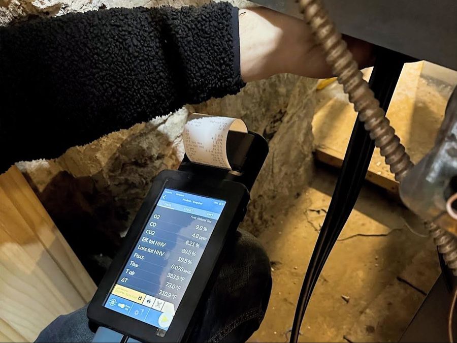Flue gas analyzer printing combustion readings for oxygen, carbon monoxide and efficiency during a boiler tune-up in a NYC basement