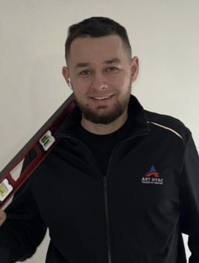 Stan T., technical director at Art HVAC, holding a level in a branded Art HVAC uniform jacket