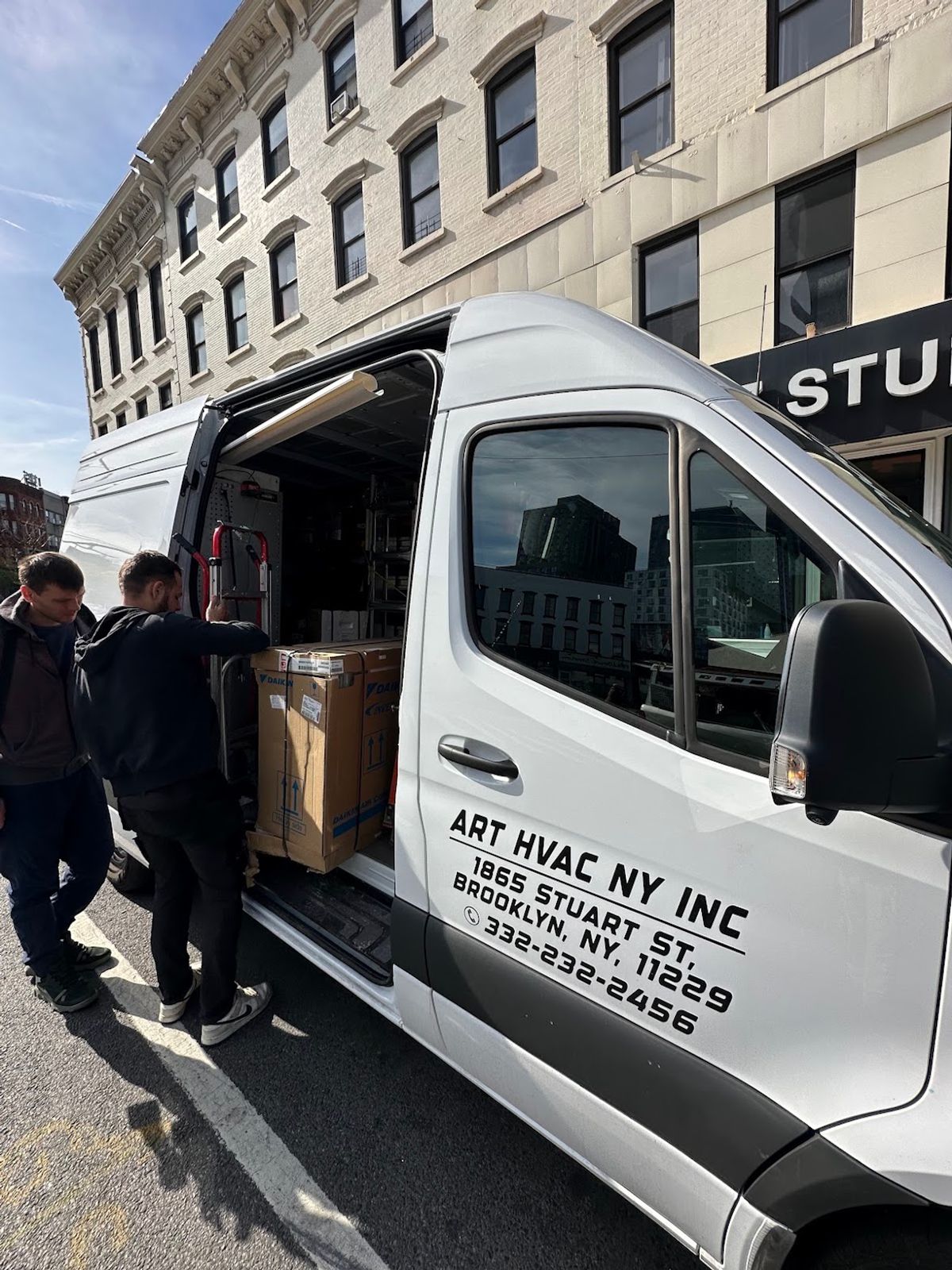 Art HVAC crew unloading new Daikin equipment from the service van outside a Brooklyn building on installation day