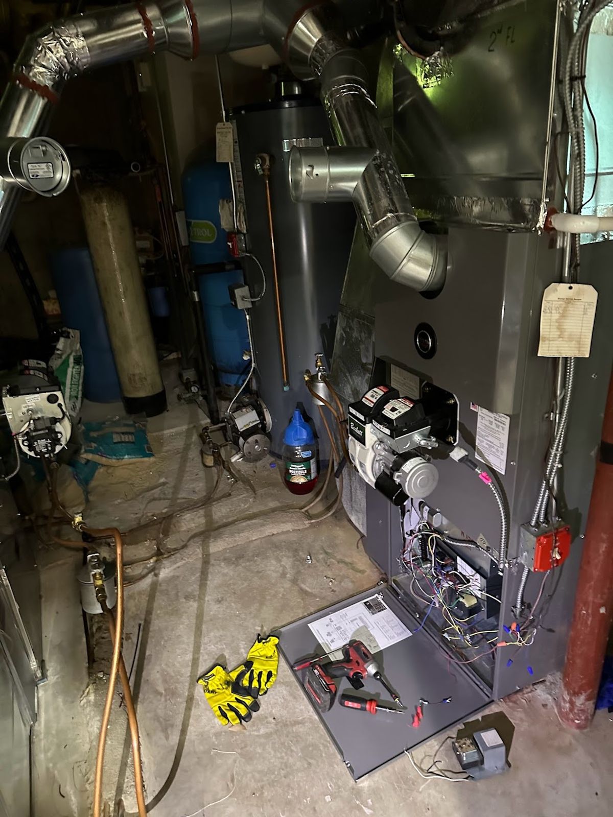 Gas furnace opened for diagnosis in a basement during a no-heat service call, with tools laid out on the access panel