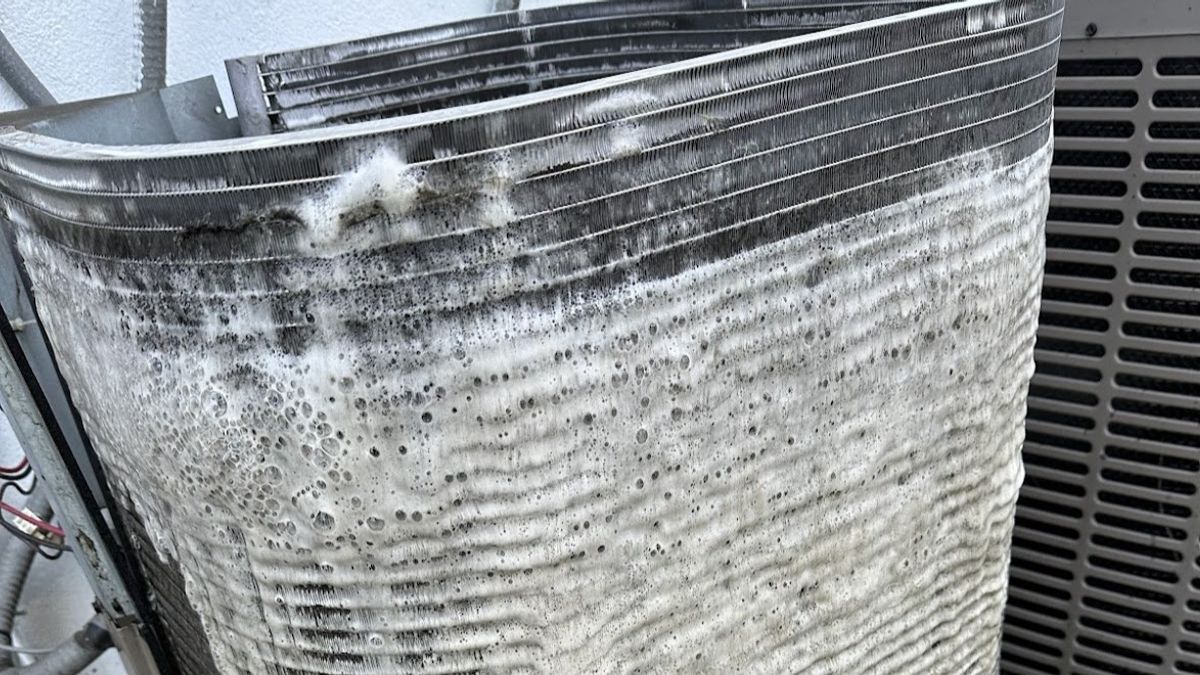 Art HVAC Technician Spraying Foaming Coil Cleaner on a Commercial Condenser Coil at a NYC Office HVAC Maintenance