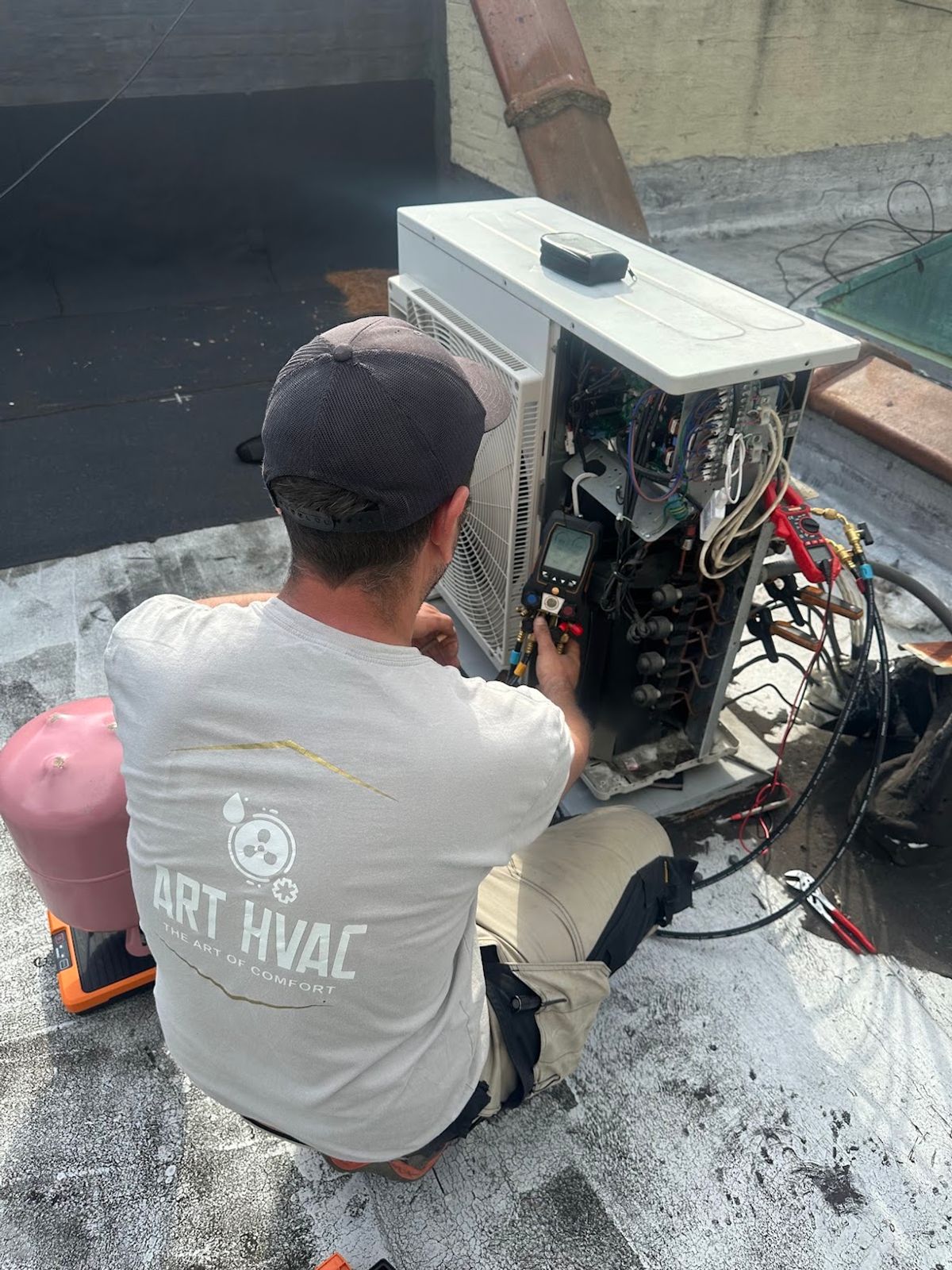Art HVAC technician working inside the control panel of a rooftop HVAC unit on a Brooklyn roof