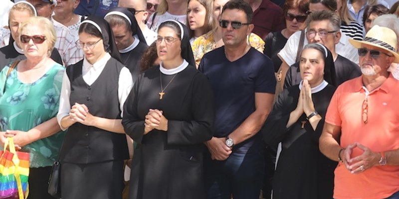 NEOBIČNA KOMBINACIJA Pored časnih sestara u Sinju gospođa s torbicom u duginim bojama