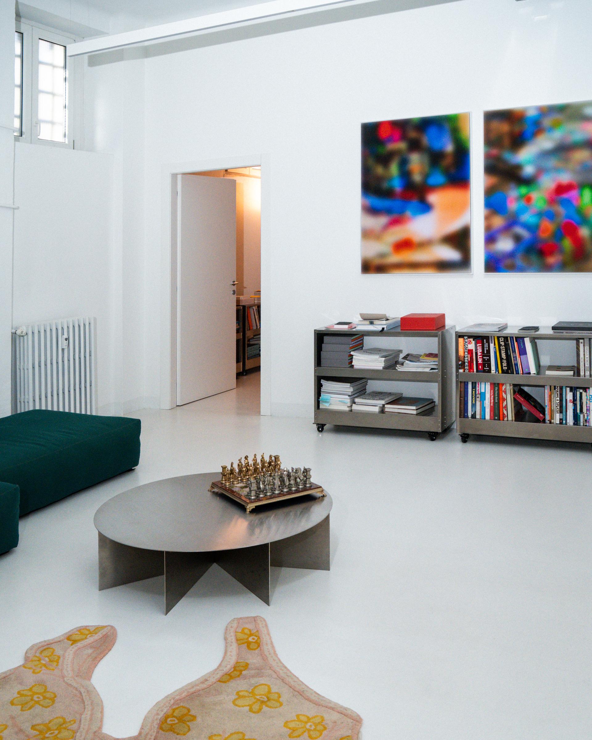 Giga studio interior with bookshelves, a chessboard and framed works.