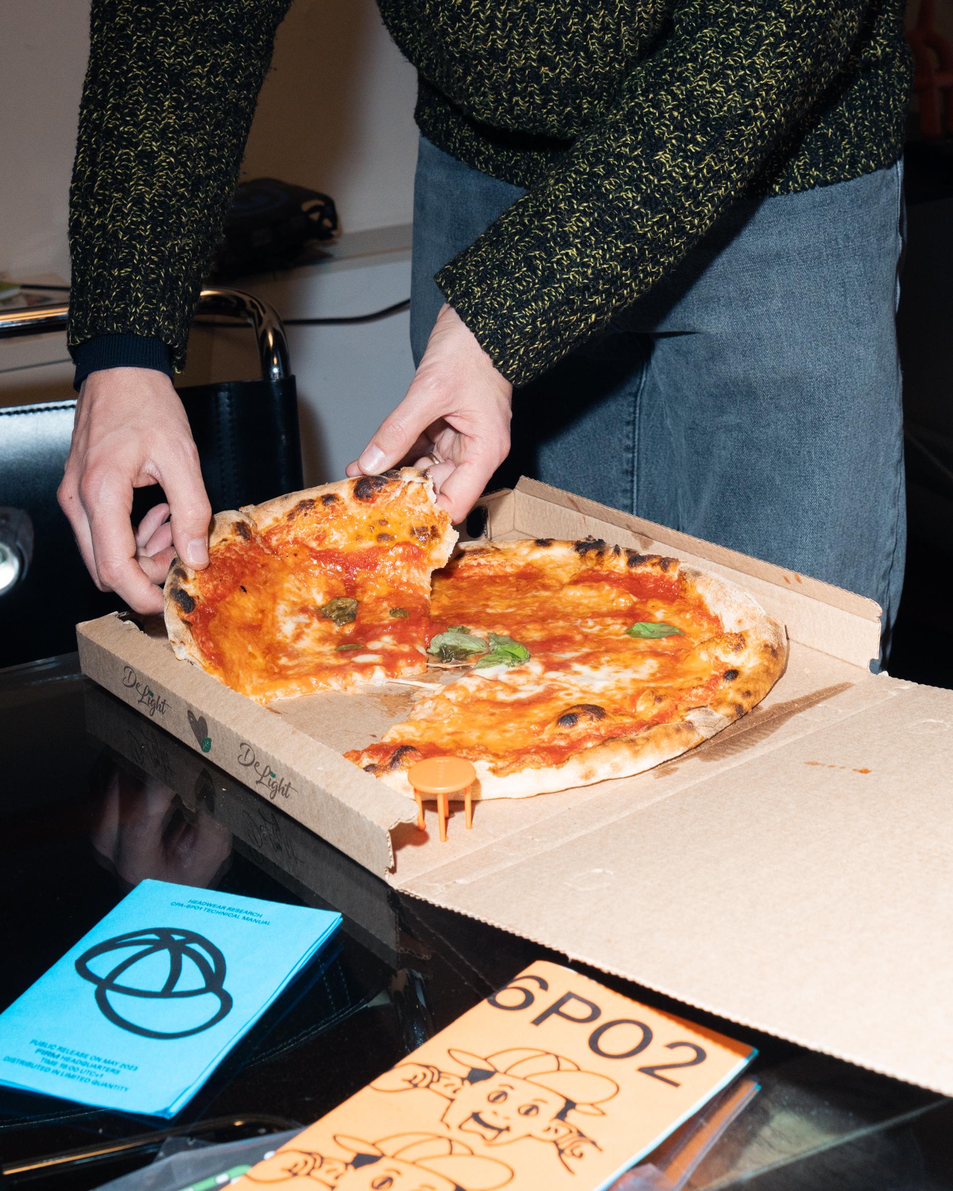 Participant serving pizza beside 5+1 printed matter.