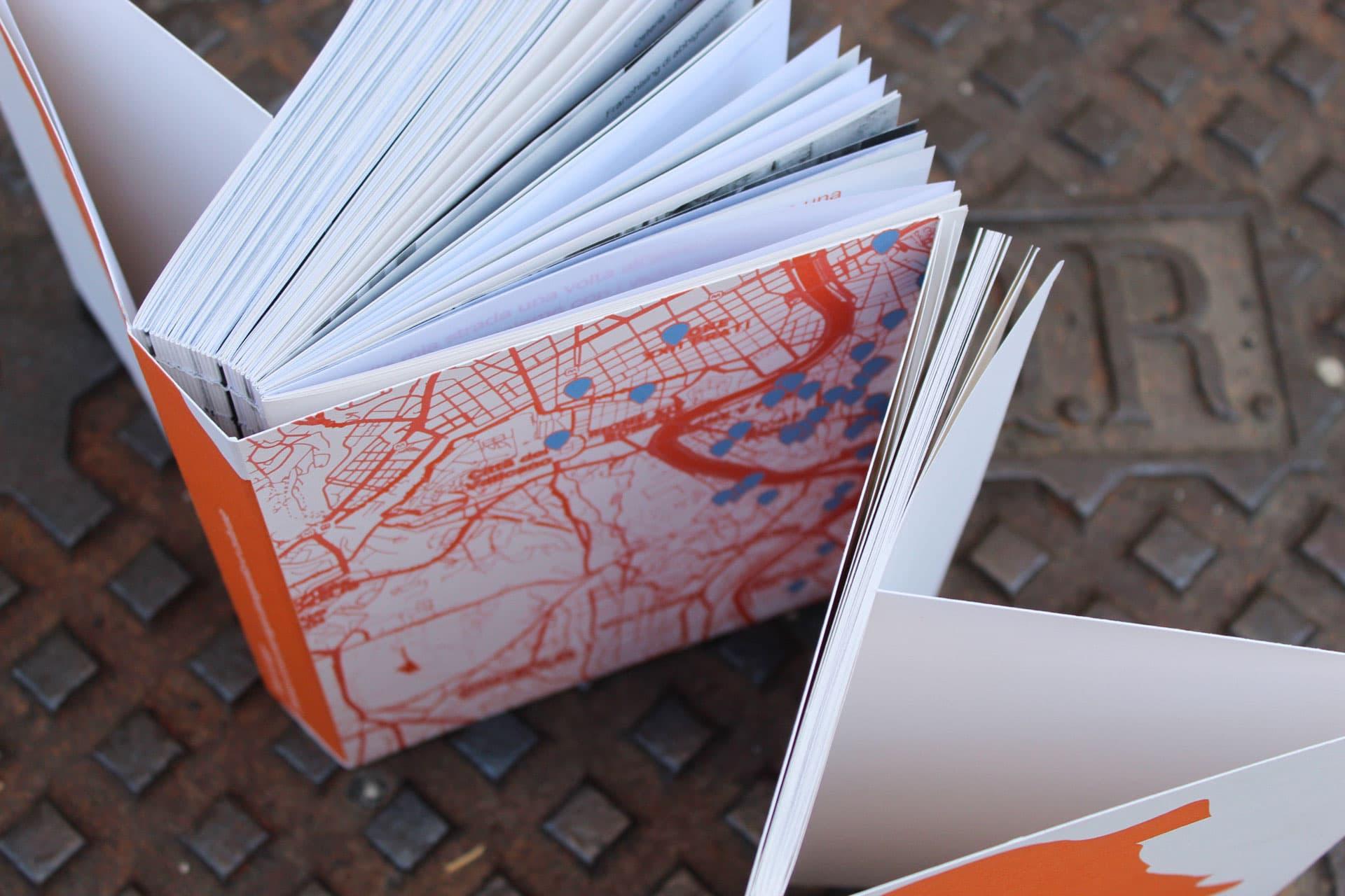 Open Stato in Luogo book with red Rome street-map pages on patterned metal flooring.