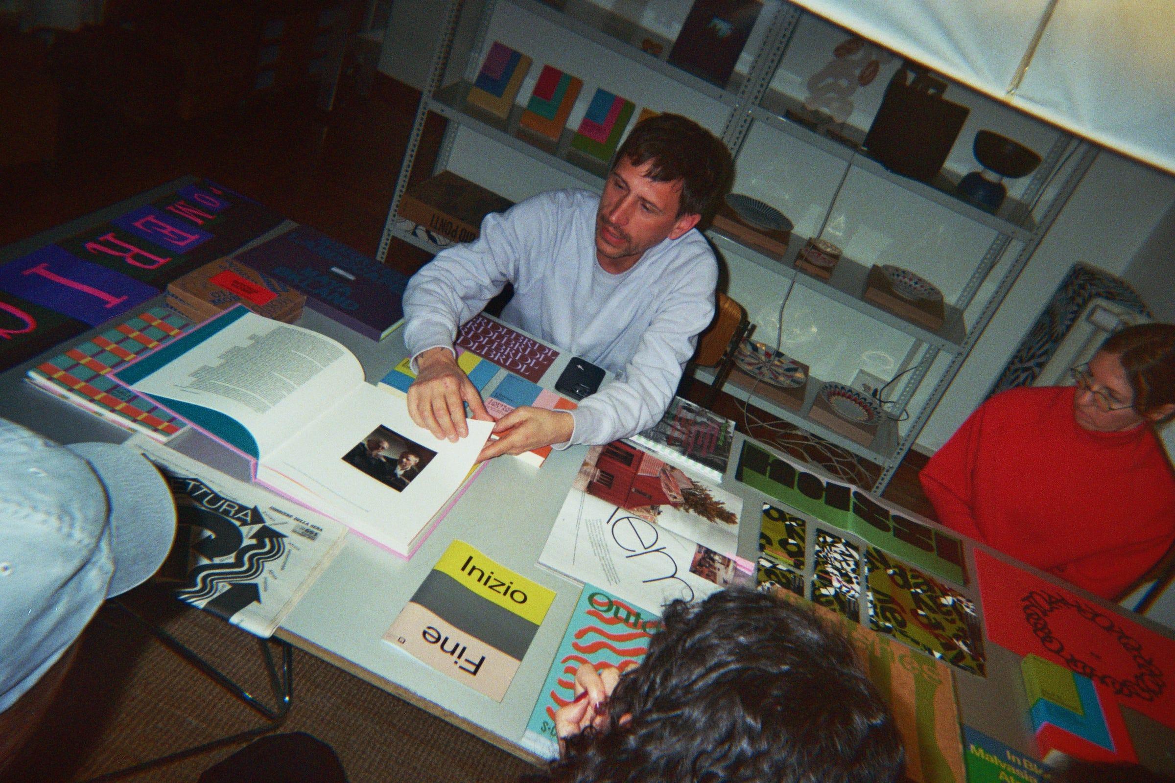Host showing an open book to attendees around the LaTigre table.