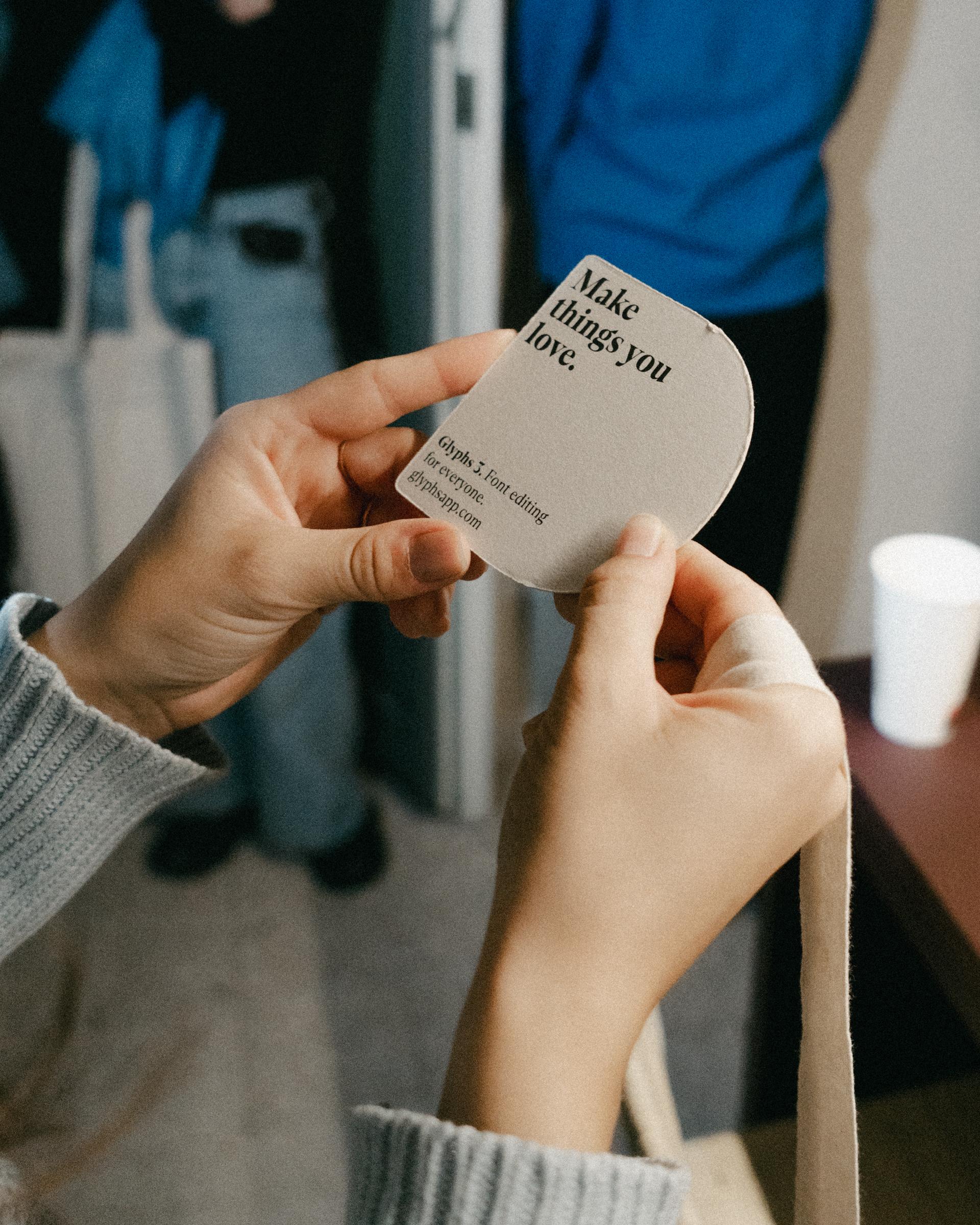 Hands holding a small card reading "Make things you love."