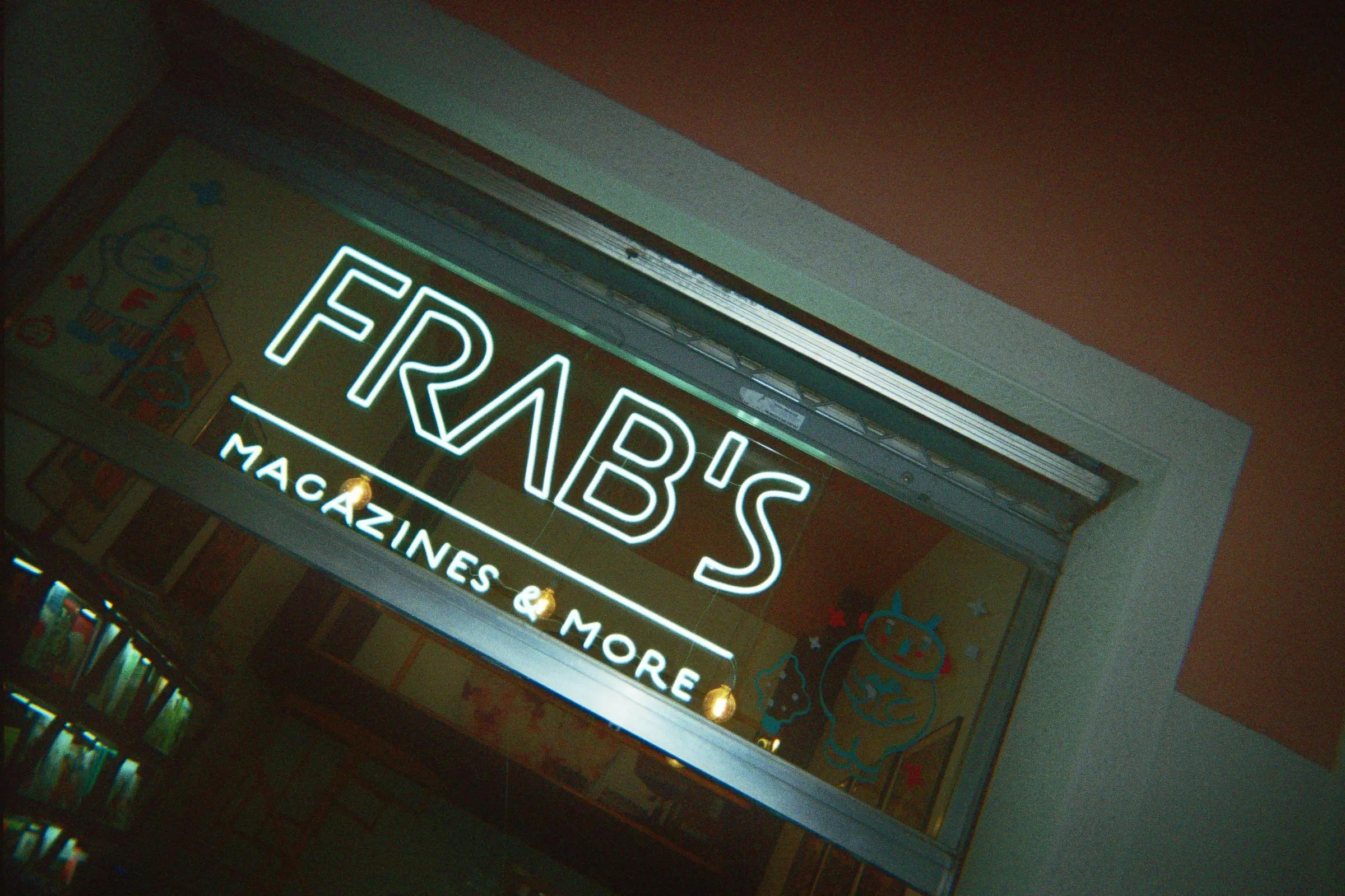 Illuminated Frab’s Magazines & More sign above the entrance to the shop.
