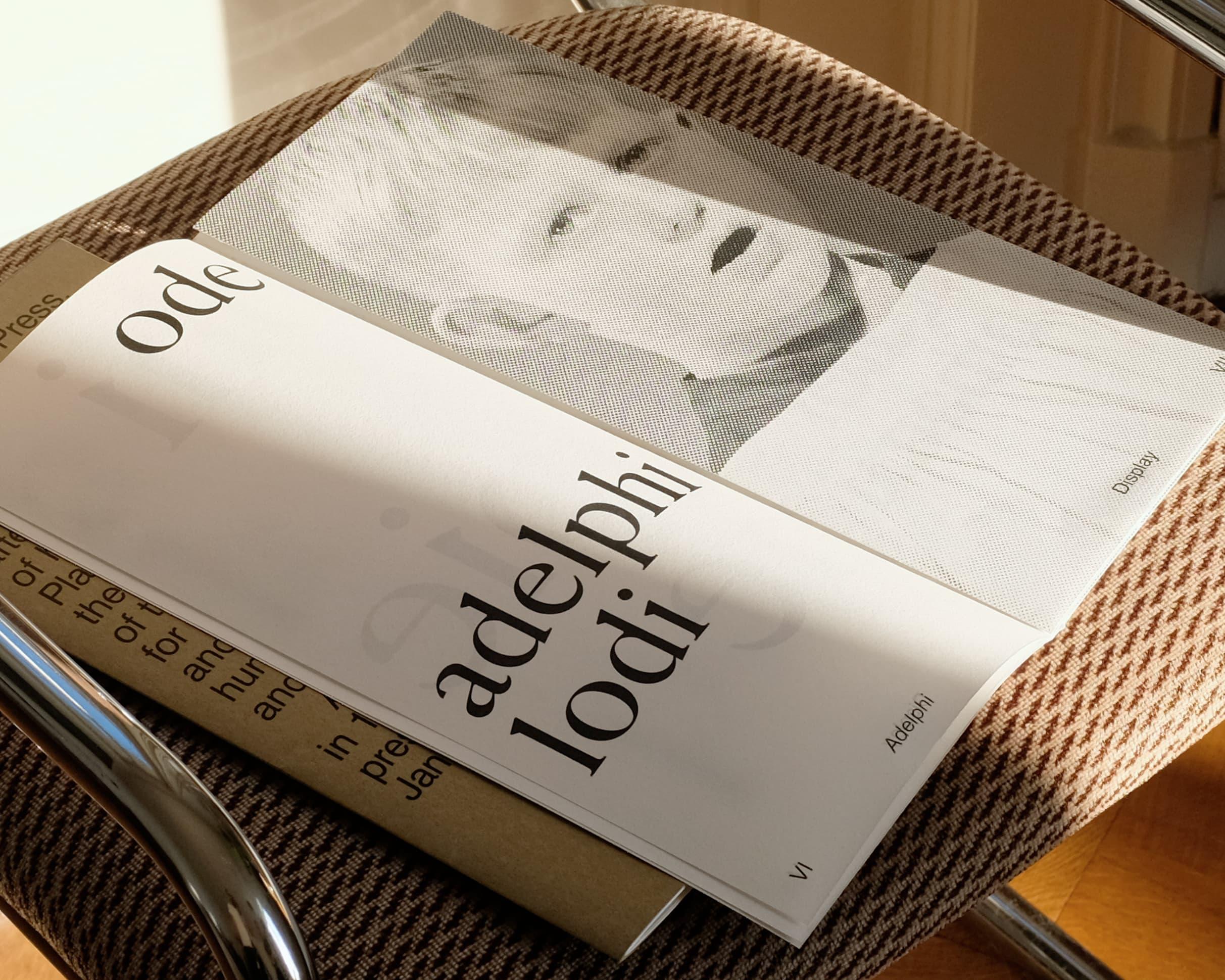 Adelphi publication with a monochrome portrait cover resting on a patterned chair.