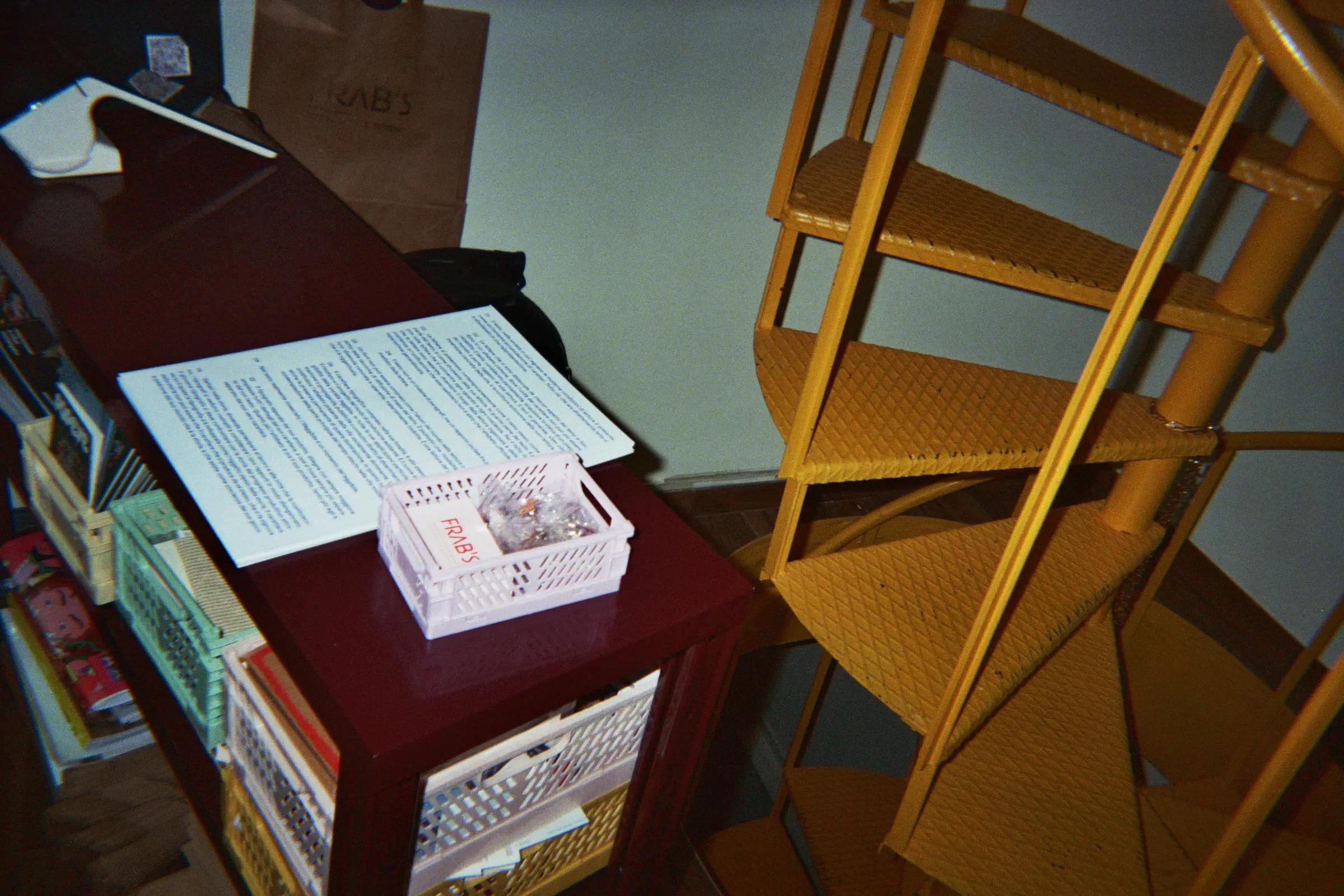 Magazine display, printed sheet and Frab's crate beside a yellow folding chair.