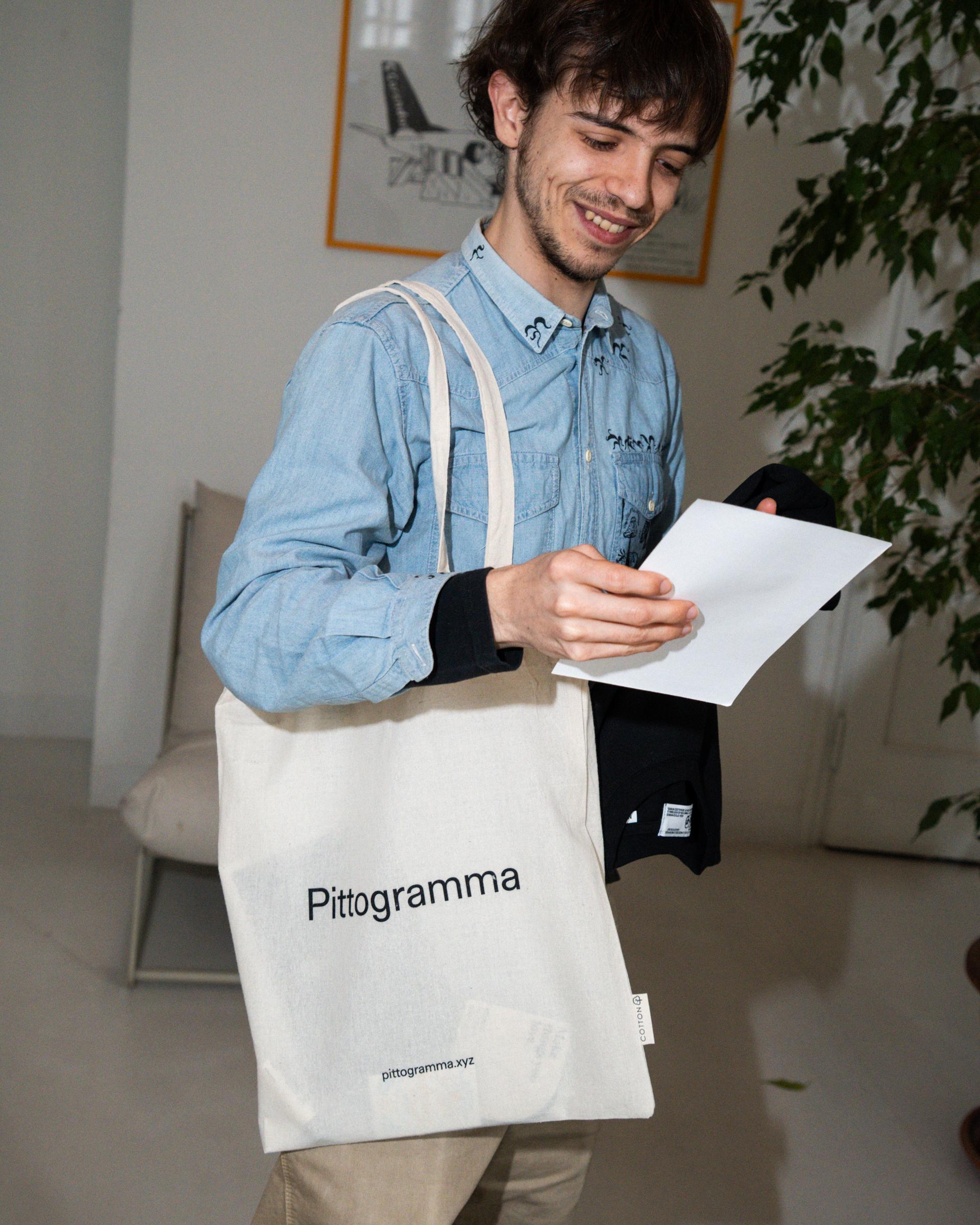 Attendee holding a black Giga sweatshirt and carrying a Pittogramma tote bag.