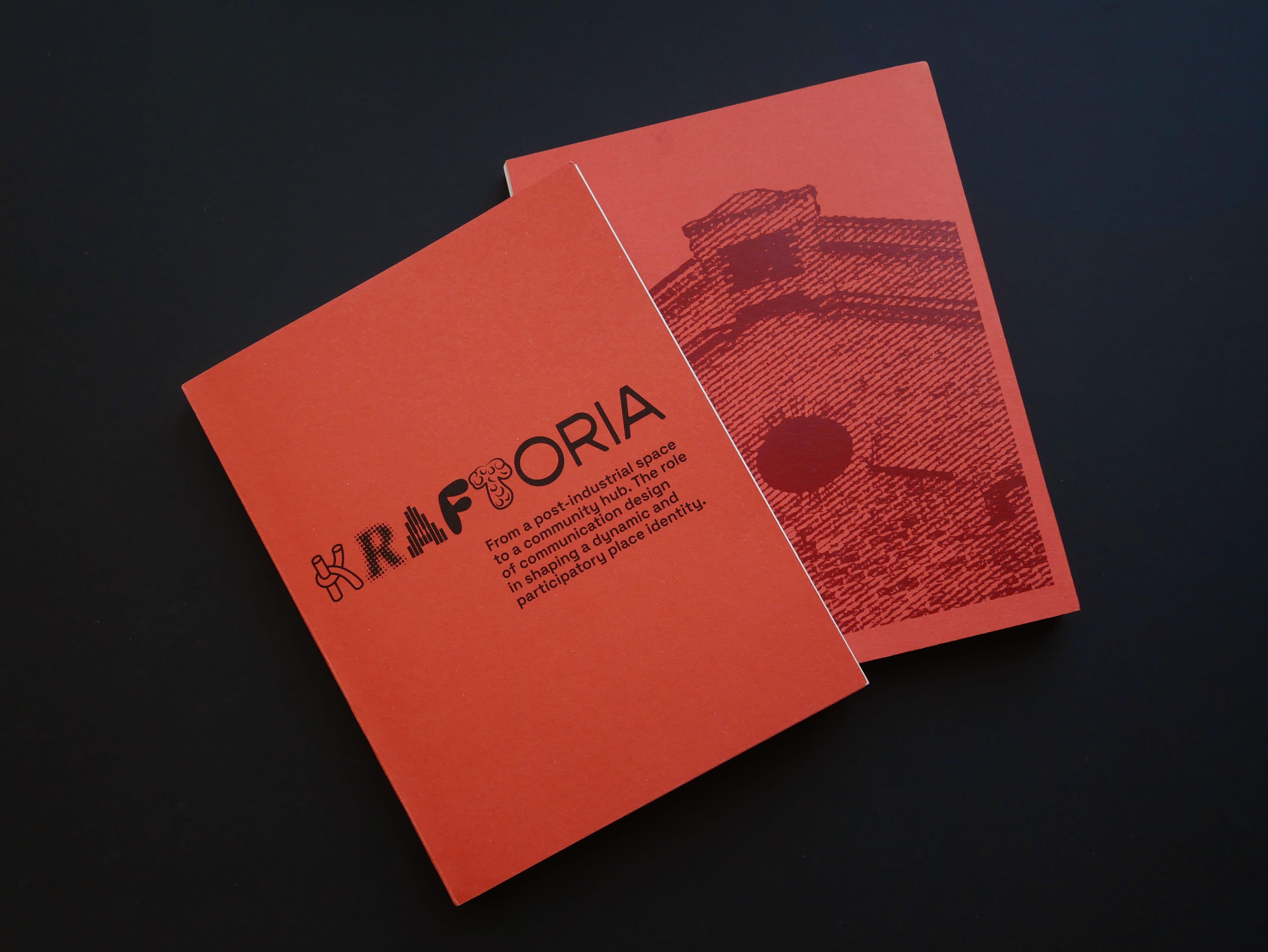 Two red-orange Kraftoria booklets on a black background.