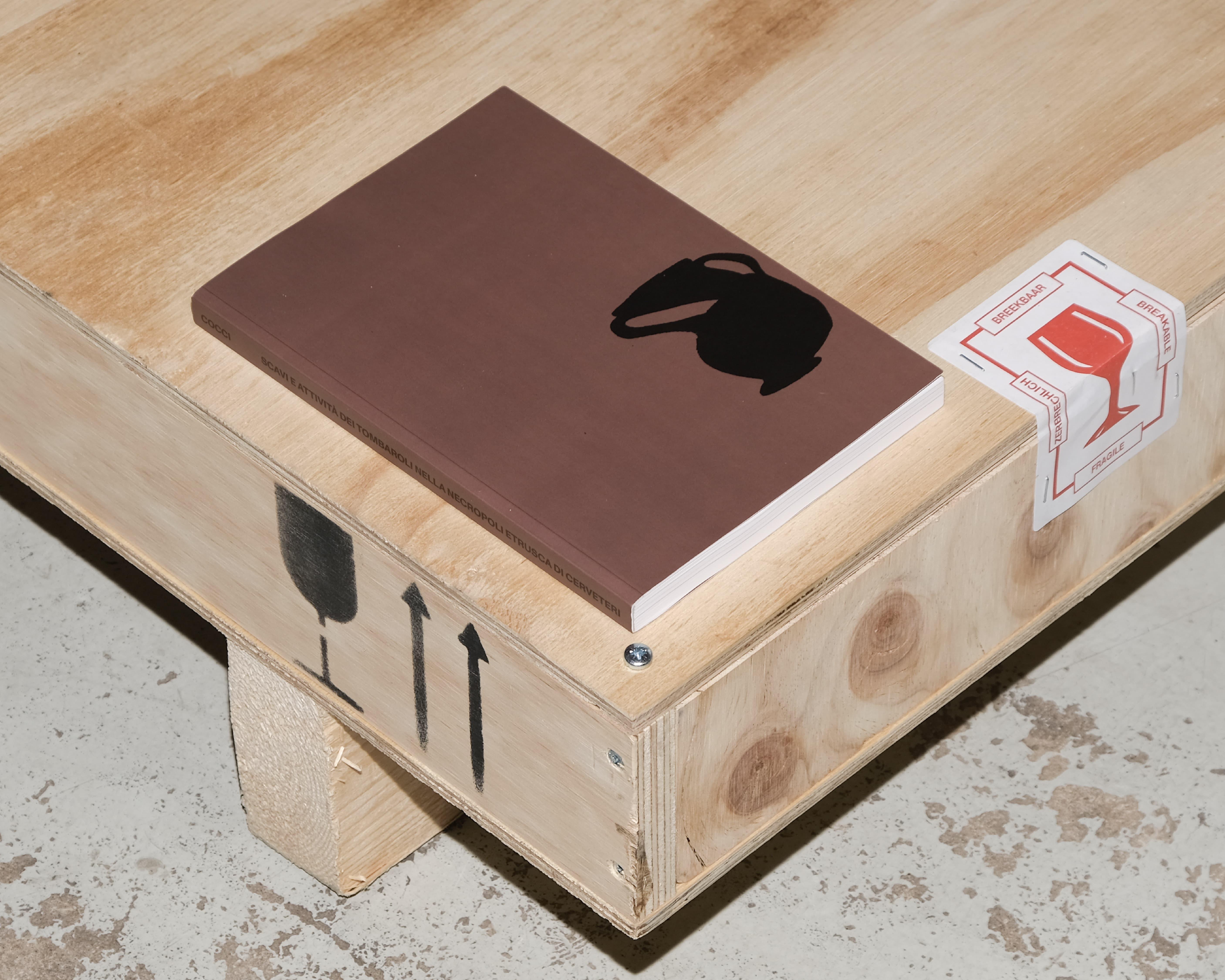 Brown booklet with a black horse silhouette on a wooden crate.