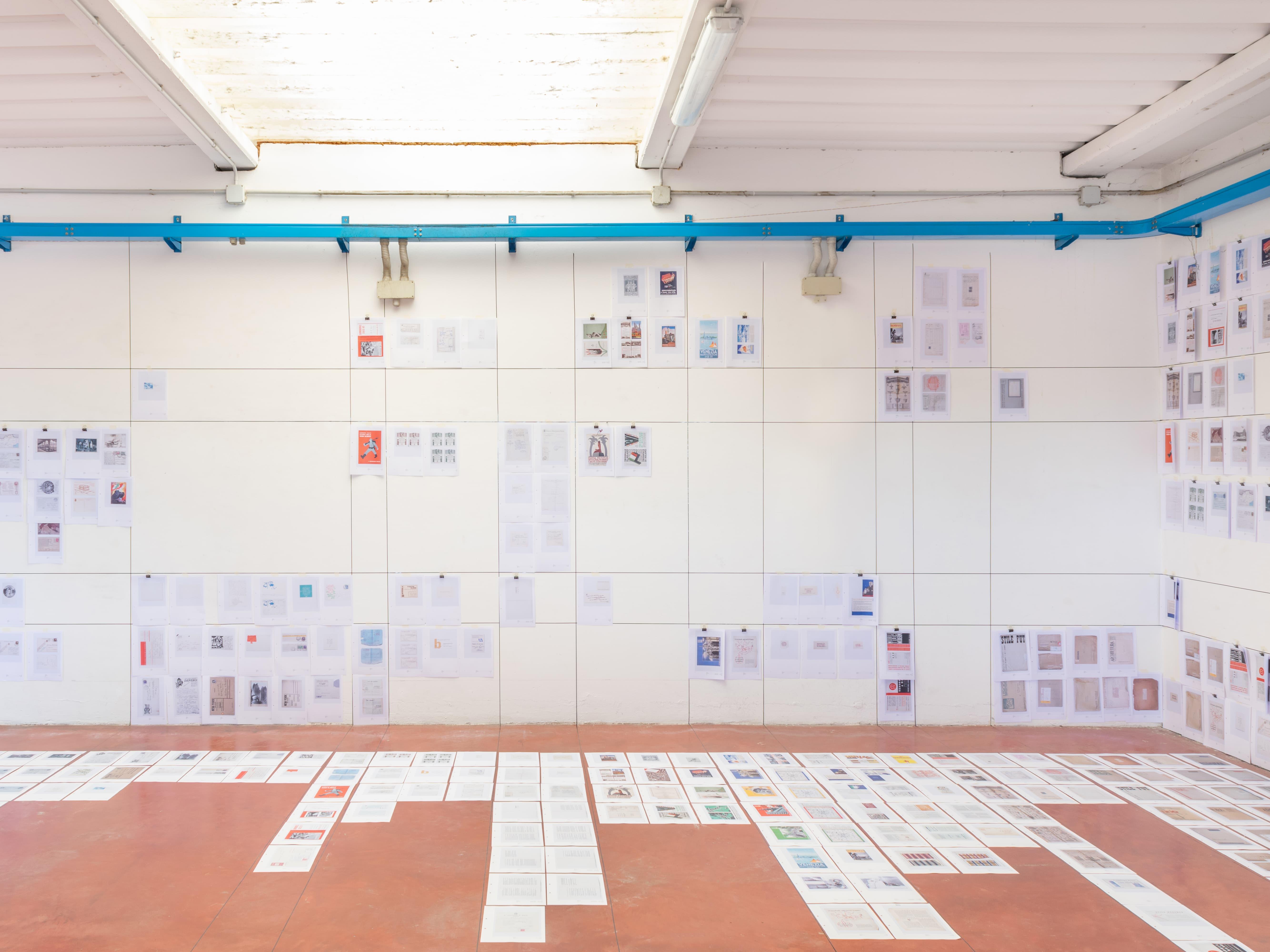 Ephemera exhibition wall with printed sheets arranged in a grid.
