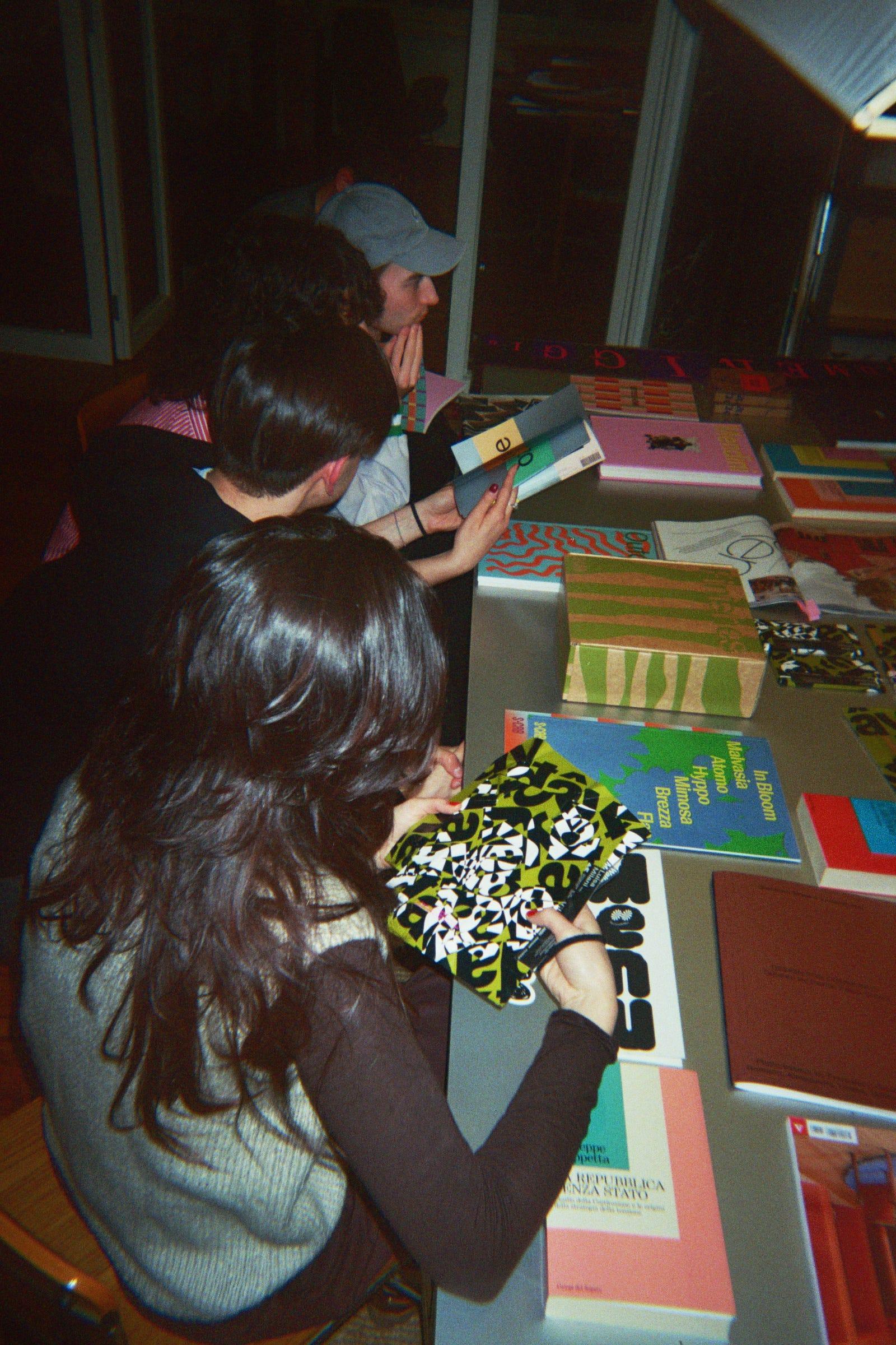 Attendees looking through books and printed work at the LaTigre table.