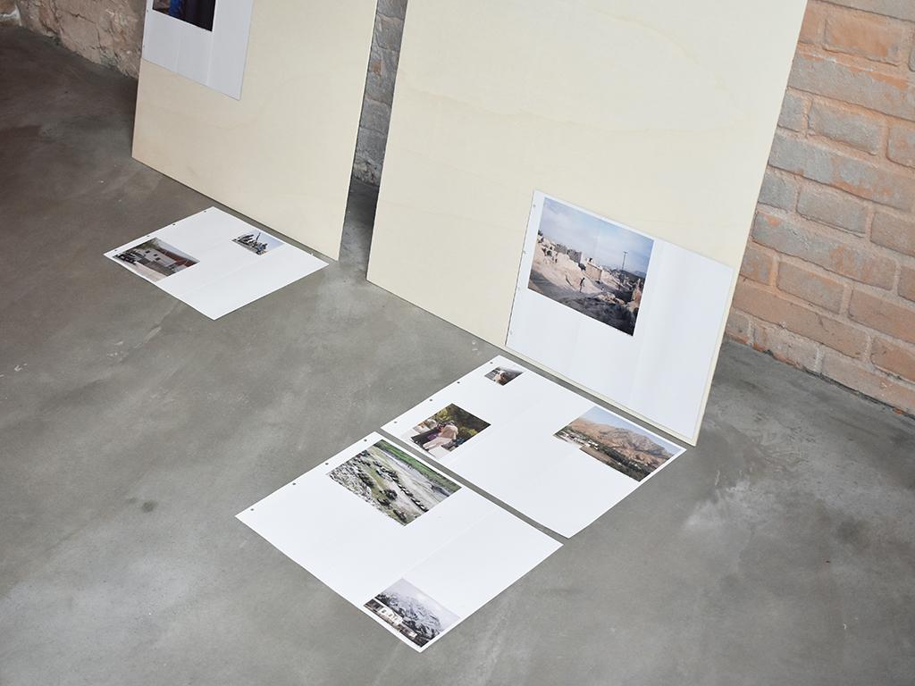 Detail of the Brick by Brick exhibition with printed photographs and boards arranged on the floor.