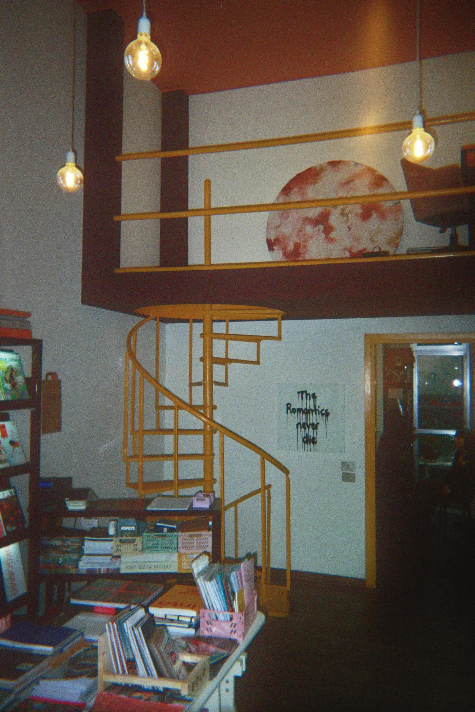 Yellow spiral staircase above shelves and stacks of magazines at Frab's.